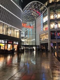 the inside of a shopping mall at night with people walking around and lights shining on the buildings