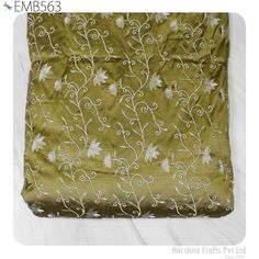 an embroidered fabric with white flowers and vines on olive green, shown from the front