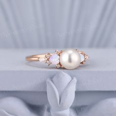 an opal and diamond ring on top of a white cloth with a rosette