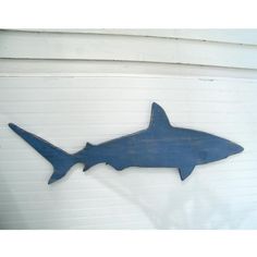 a blue metal shark sign hanging on the side of a white garage door in front of a building