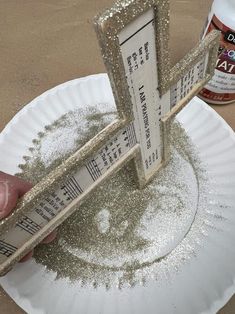 a person is holding two pieces of paper with glitter on them and measuring the length