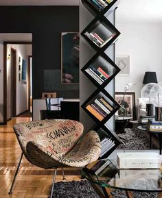 a living room filled with furniture and a tall book shelf next to a glass table