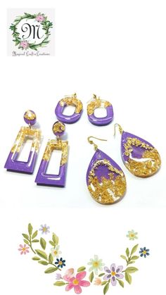 the purple and gold earrings are next to each other on a white surface with flowers