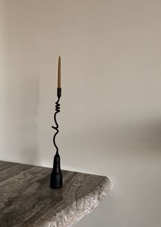 a black candle holder on top of a marble table with a white wall in the background