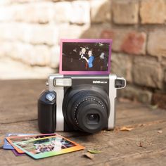 an old camera sitting on top of a wooden table next to some cards and photos