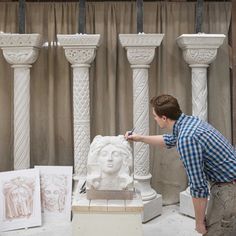 a man is working on a statue in front of some pillars and other art work