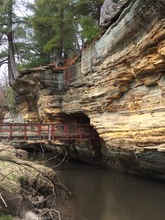 a wooden bridge over a river next to a cliff