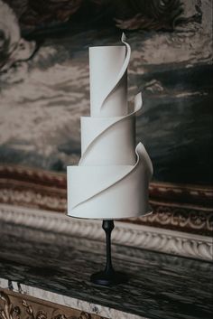 a white cake sitting on top of a wooden table next to a large wall painting