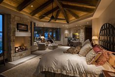 a large bedroom with a fireplace in the center and stone walls on both sides, along with two couches