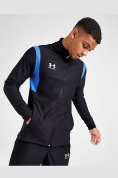 a man in black and blue tracksuits is looking down at his hand on his hip