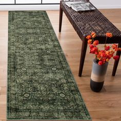 a large green rug in the middle of a room with a bench and flowers on it