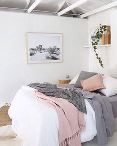 a bed with blankets and pillows in a bedroom next to a wall hanging on the wall