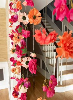 colorful paper flowers hanging from the ceiling in front of a stairway way with stairs and railings