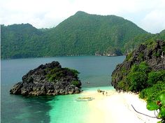 the beach is surrounded by green mountains and blue water