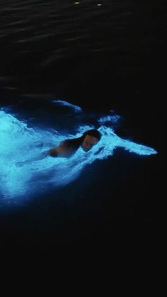 a man is swimming in the water with blue lights on his body and head as he swims