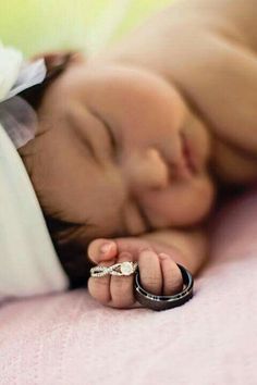 a baby sleeping on top of a pink blanket next to a pair of black rings