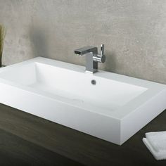 a white bathroom sink sitting on top of a wooden counter next to a green plant