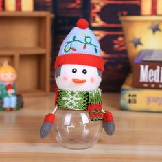 a snowman figurine sitting on top of a wooden table next to other toys