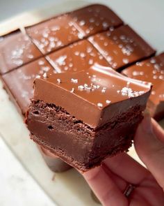 a hand holding a piece of chocolate cake