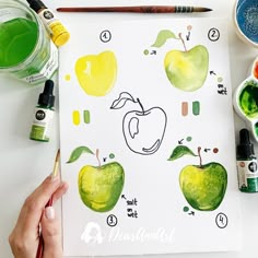 someone is painting an apple on paper with watercolors and paintbrushes next to it