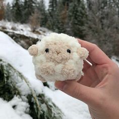 a hand holding a small stuffed animal in the snow