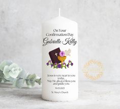 a white candle with an image of a cake on it and flowers in the background