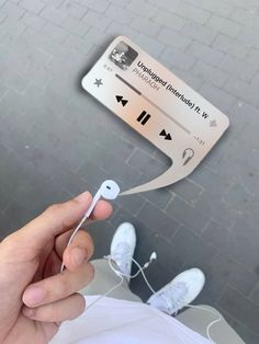 a person holding an earbud in front of a sign with headphones attached to it