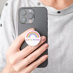 a person holding an iphone in their hand with a button on the back of it