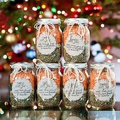 six jars filled with spices sitting on top of a table next to a christmas tree