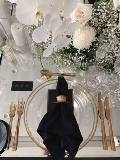 a black napkin sits on top of a plate next to gold forks and silverware