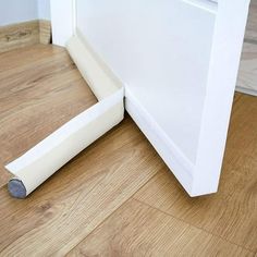 the corner of a room with a white wall and wood flooring next to it