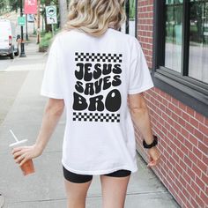 a woman is walking down the sidewalk wearing a t - shirt that says jesus saves broo