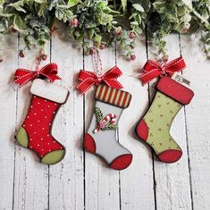 three decorated christmas stockings hanging from wooden boards