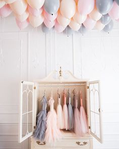 balloons are hanging from the ceiling above a dresser with tulle skirtes on it