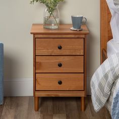 a nightstand with flowers on it next to a bed