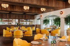 a restaurant with yellow chairs and wooden tables