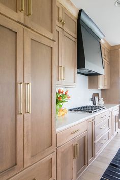 a kitchen with wooden cabinets and white counter tops, an oven hood over the stove