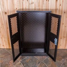 an open black cabinet with holes in the middle on a tile floor next to a wooden wall