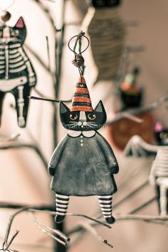 a black and white cat ornament hanging from a tree with decorations in the background