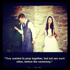 a bride and groom standing in front of a stone wall with their hands on each other