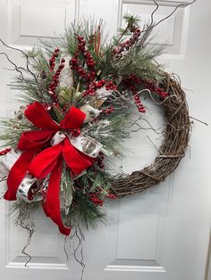 a wreath with red ribbon and bells hanging on the front door