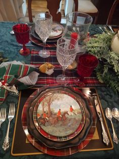 a place setting with plates, silverware and flowers on a plaid tablecloth covered table