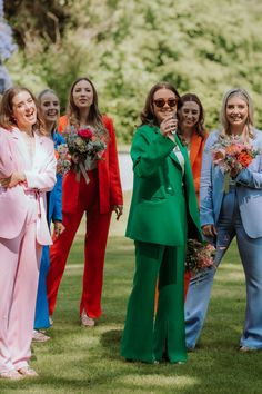 6 bridesmaids playing outdoor garden games in colourful suits. Pink, blue, red, green, orange and light blue Bridal Party In Suits, Non Formal Wedding Attire, Bridesmaid In Suits, Pant Suit Bridal Party, Eclectic Bridesmaids Dresses, Bridesmaid In Suit, Fun Wedding Outfits, Colorful Fun Wedding, Festival Themed Wedding Guest Outfit