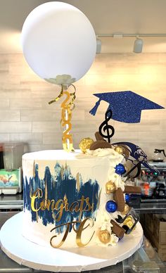 a graduation cake with music notes, balloons and confetti on the top tier