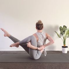 a woman is doing yoga in front of a potted plant on the floor with her legs crossed