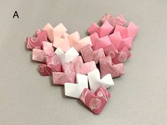 several pieces of pink and white origami are arranged in the shape of a heart