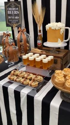 a table topped with lots of desserts and drinks on top of a black and white striped table cloth