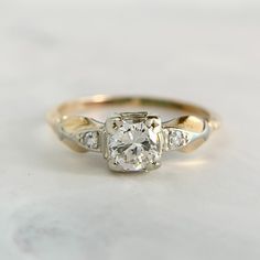 a diamond engagement ring with three stones on the band and an old - fashioned setting