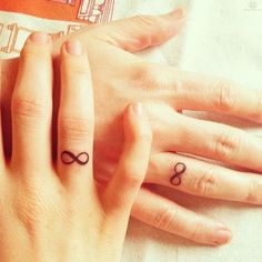 two people with matching rings on their fingers, one has an infinite sign tattooed on the middle finger