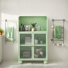 a green cabinet in a white bathroom with towels